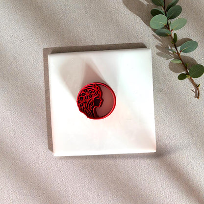 Red woman face floral clay cutter on white tile with eucalyptus branch