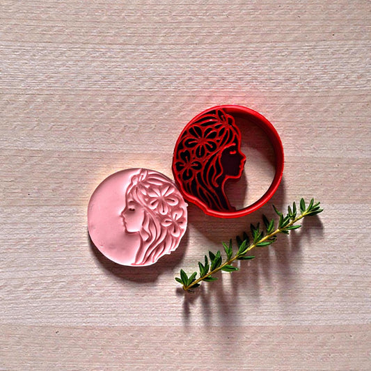 Pink floral woman impression beside red cutter and greenery on wood background