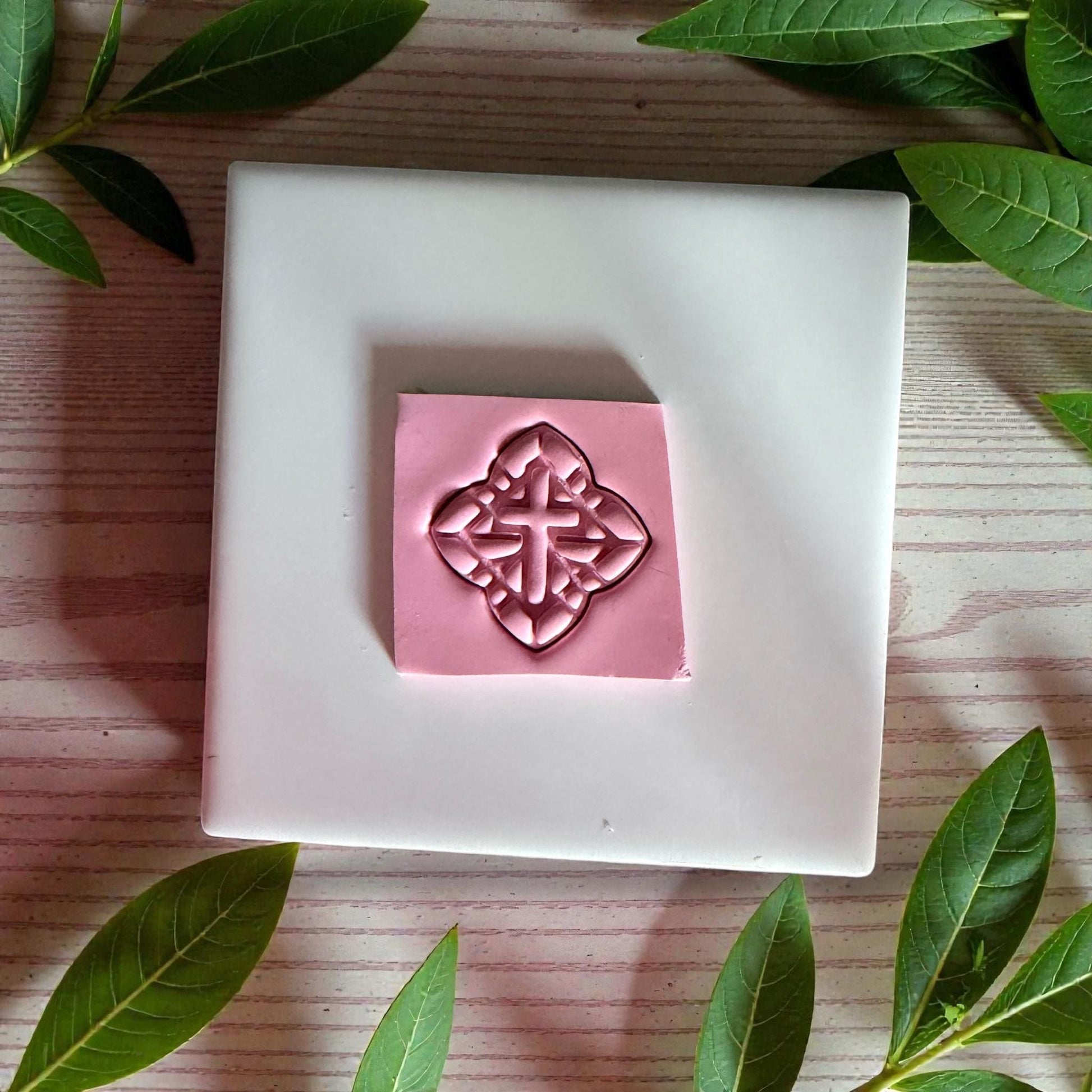 cross cutter impression pressed into pink clay slab