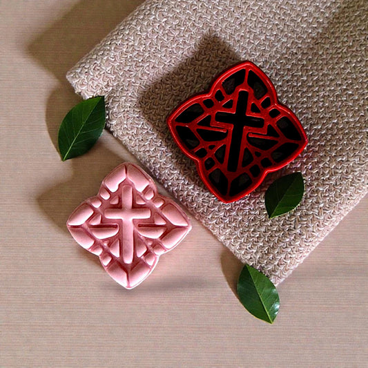 red cross cutter next to pink clay impression