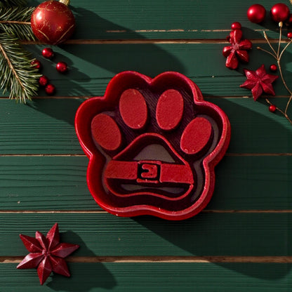 Red Santa paw polymer clay cutter on green background with ornaments