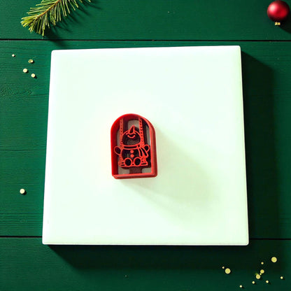 Red snowman swing cutter centered on white tile with festive decor