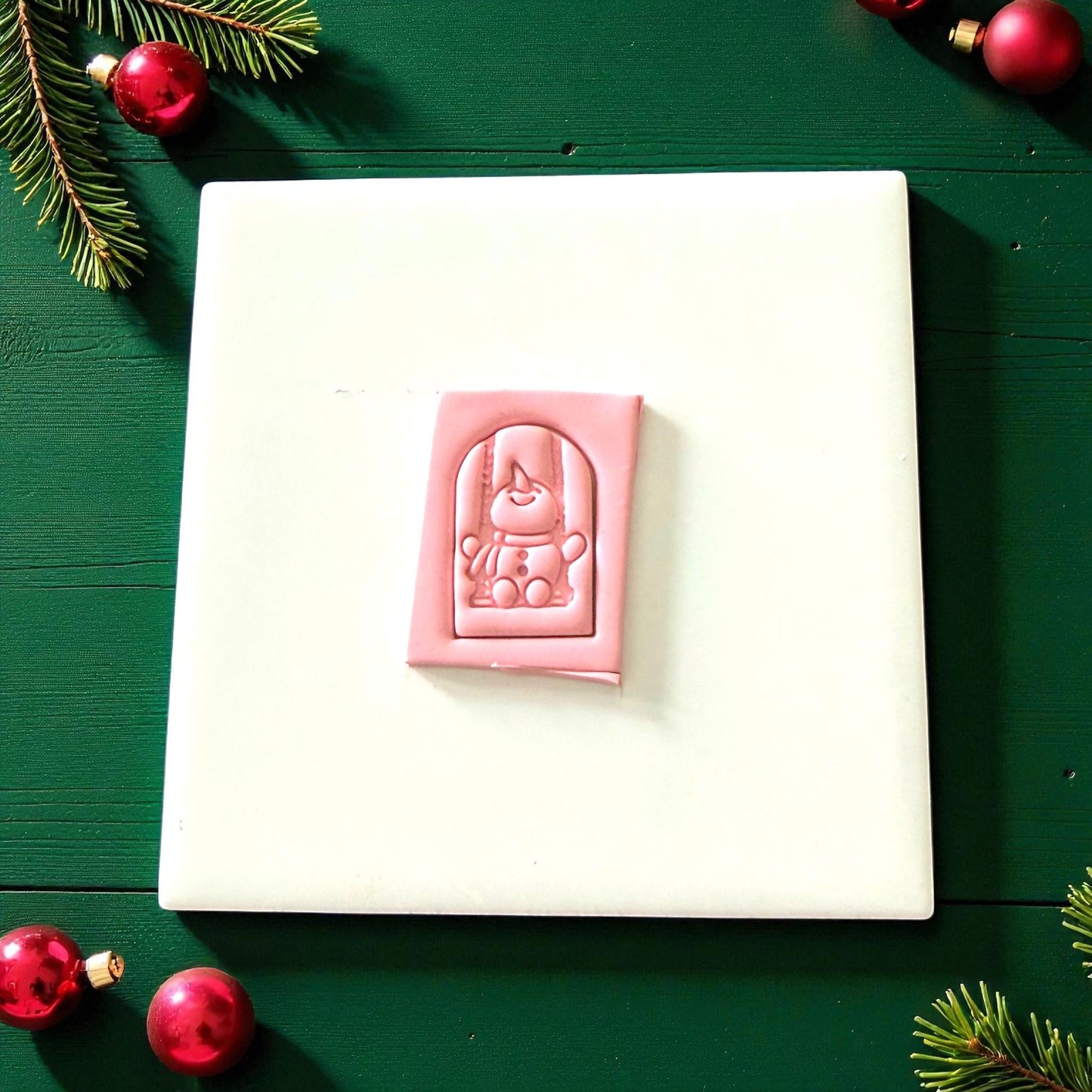 Pink snowman swing clay imprint on white tile with Christmas decor