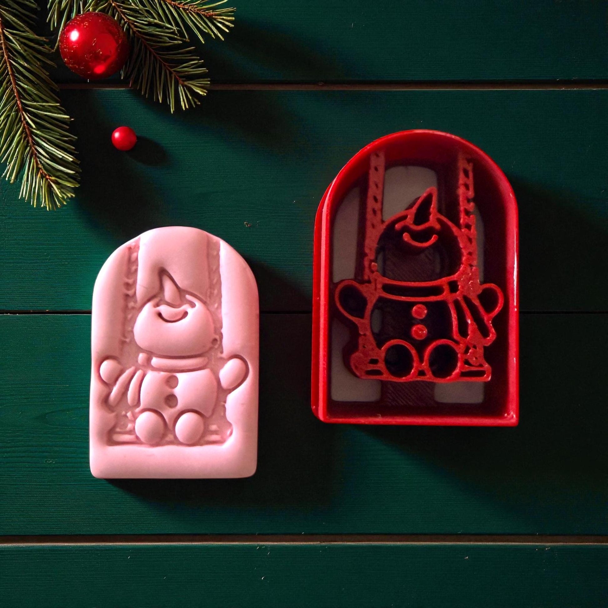 Pink and red snowman swing cutter side by side on green background