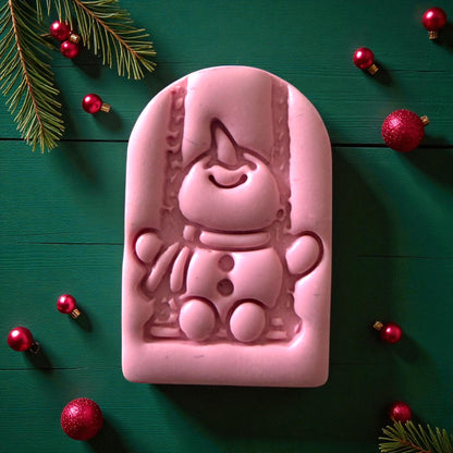 Close-up of pink snowman swing clay imprint surrounded by red ornaments