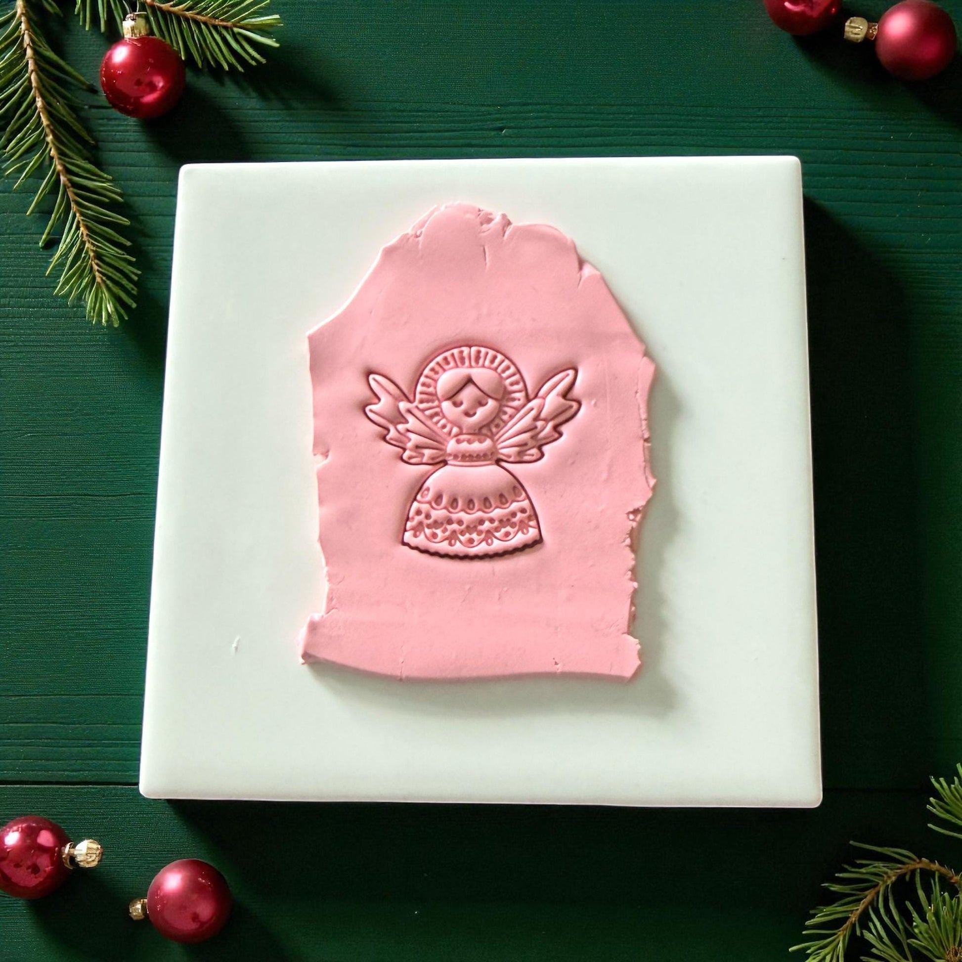 Pink angel clay imprint pressed into slab on white tile