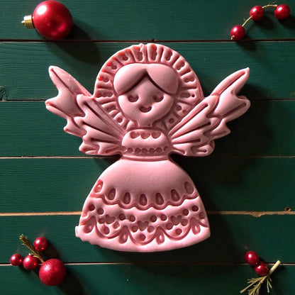 Close-up of pink angel clay imprint surrounded by red ornaments