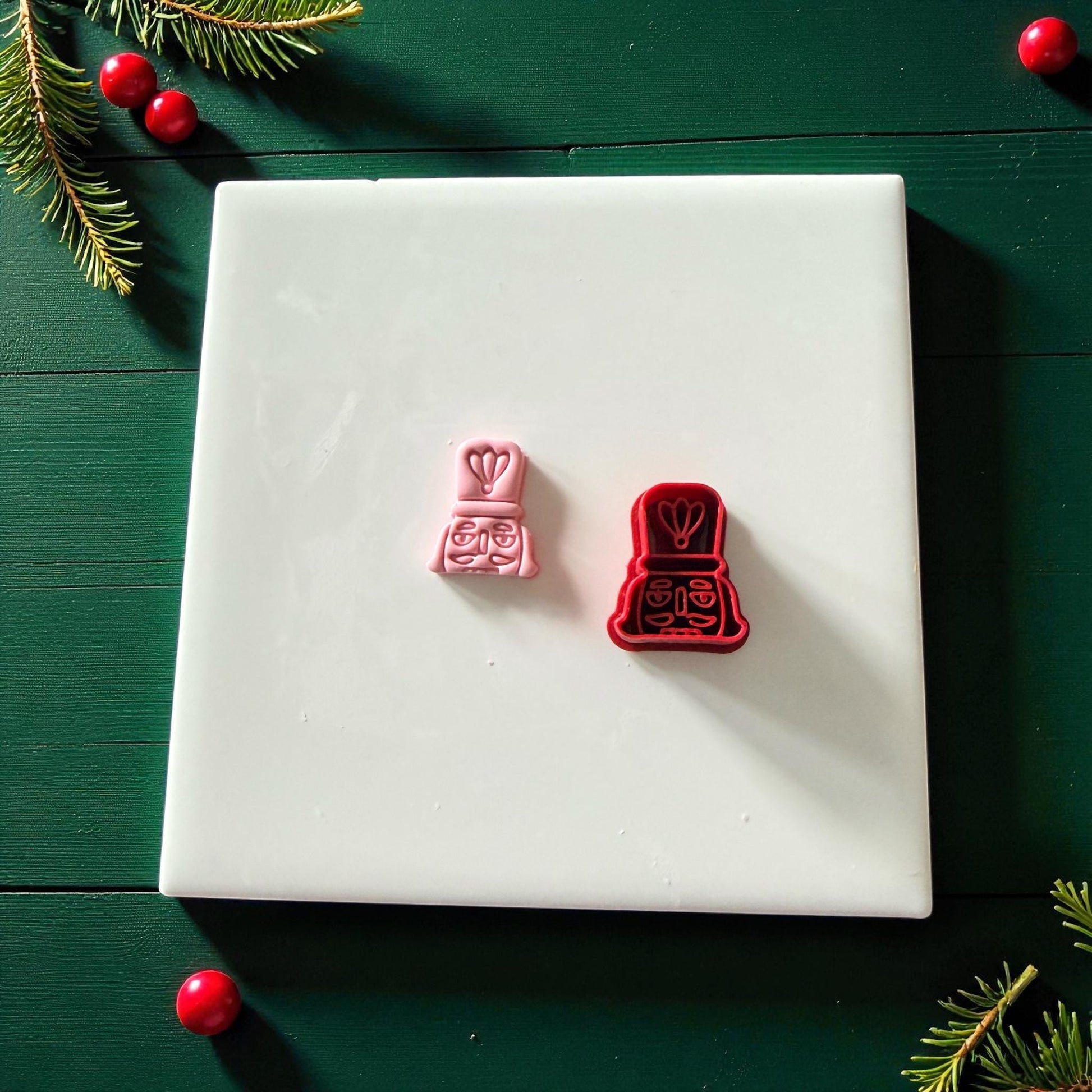 Pink and red nutcracker cutters side by side on white tile
