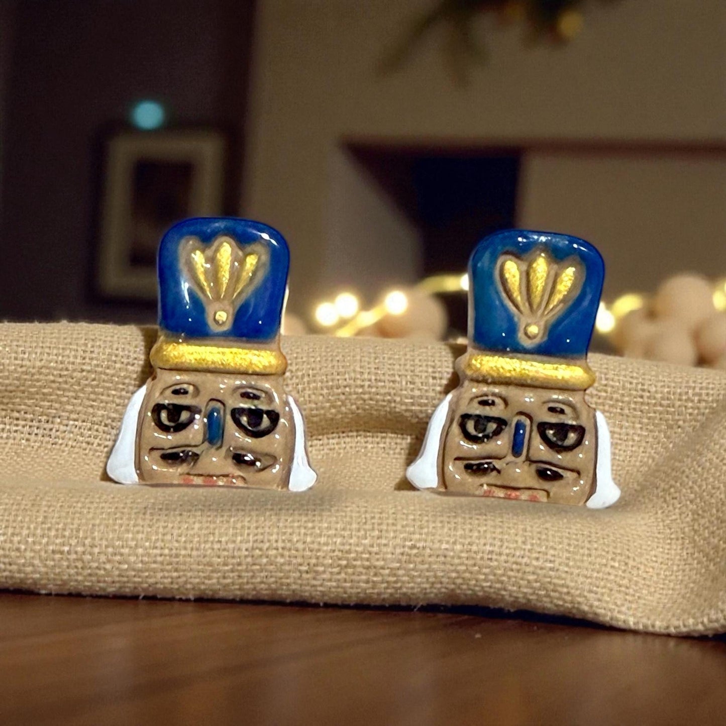 Finished nutcracker earrings with blue and gold hats displayed on burlap