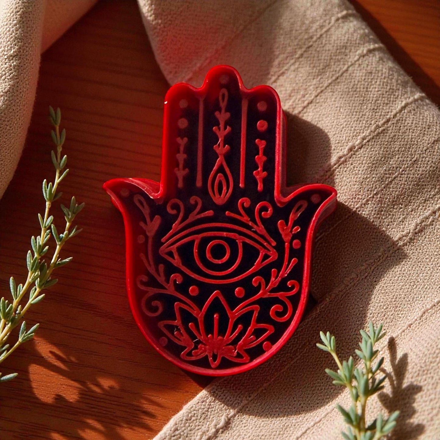 Red Hamsa Hand polymer clay cutter with evil eye design on beige fabric