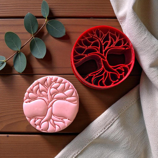 Tree of life cutter beside pink clay impression showing detailed branches and roots
