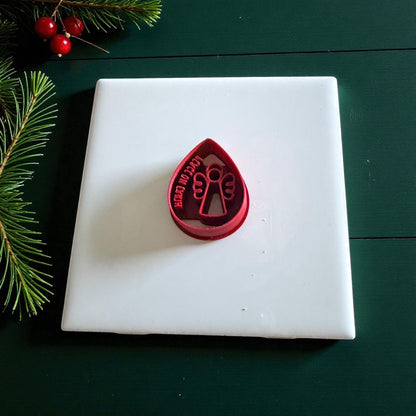 Red teardrop angel cutter on green surface with pine branches