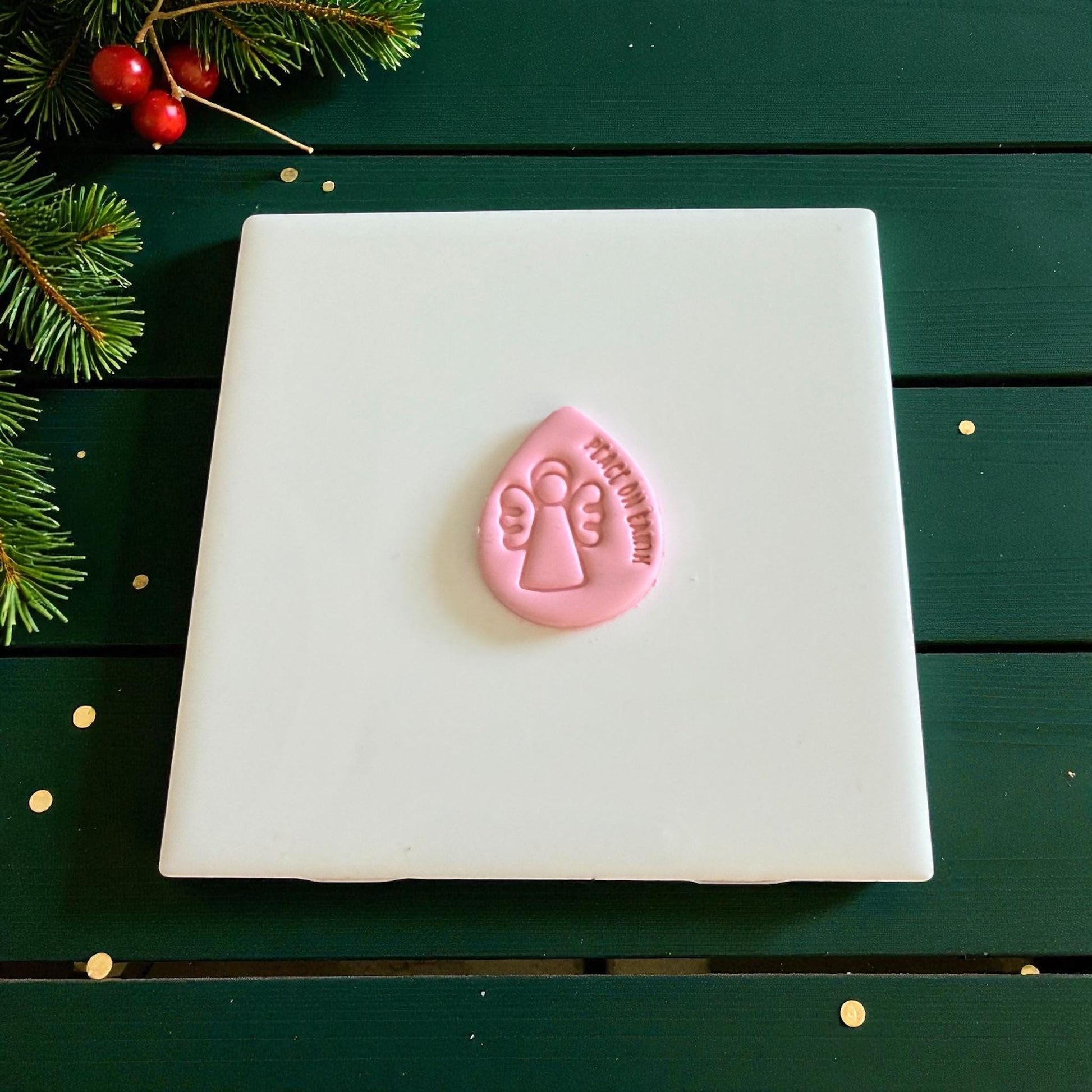 Pink teardrop clay piece embossed with angel and peace on earth text