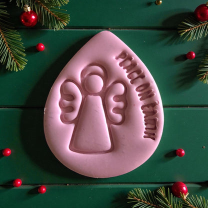 Pink teardrop clay piece embossed with angel and peace on earth text