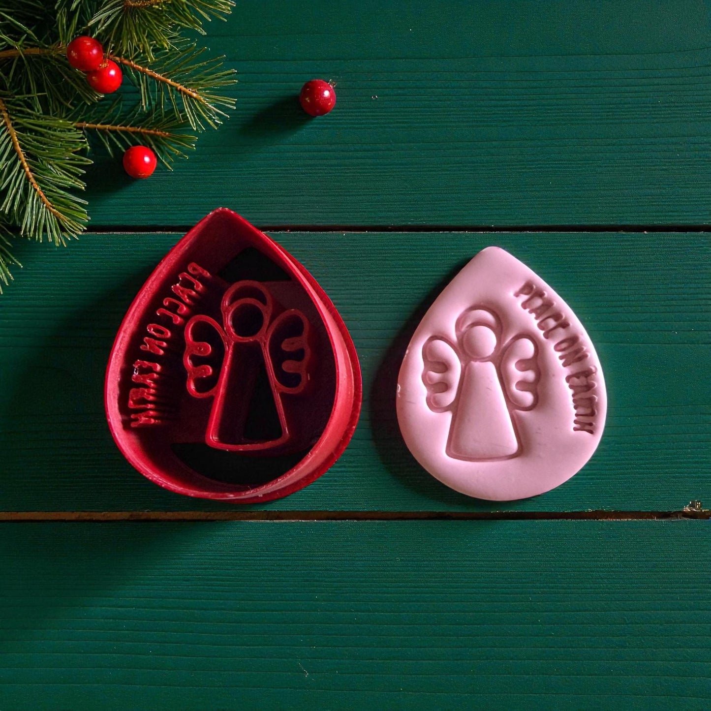 Red cutter and pink angel clay piece side by side on white tile