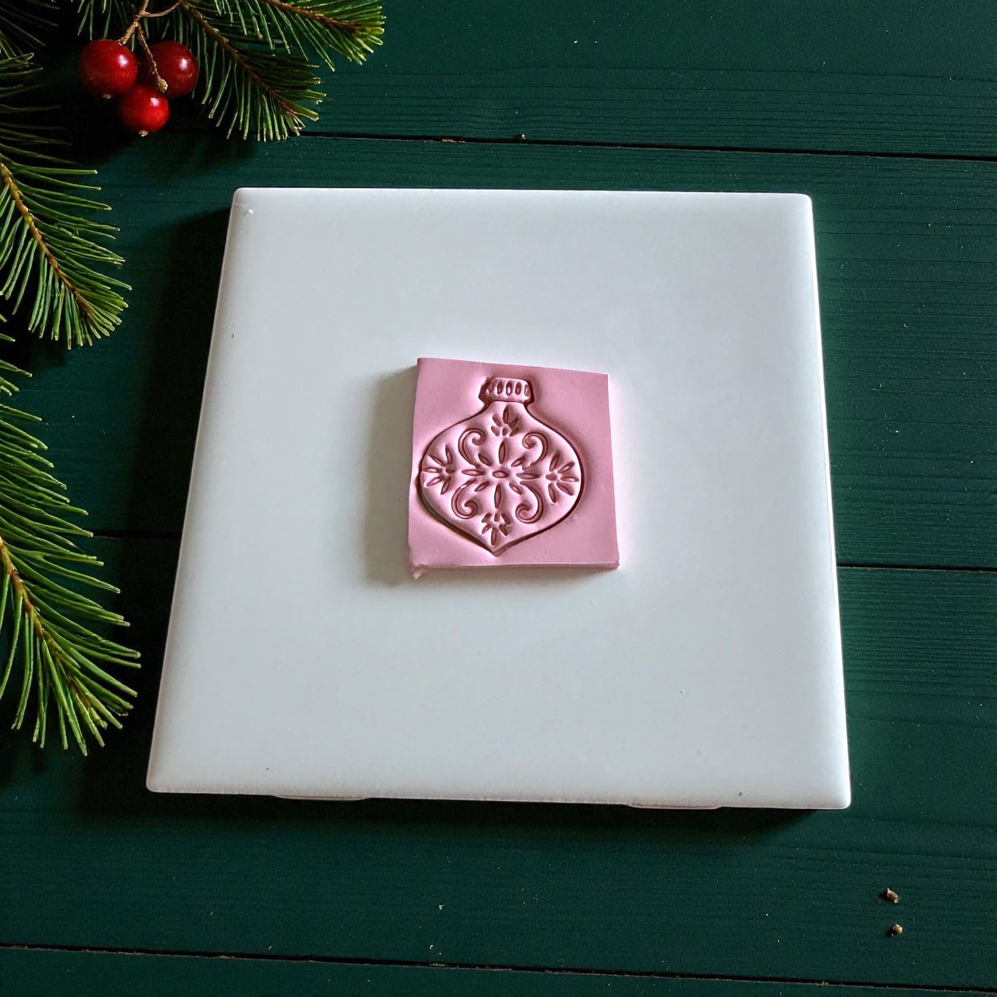 Pink clay square embossed with vintage ornament design on white tile