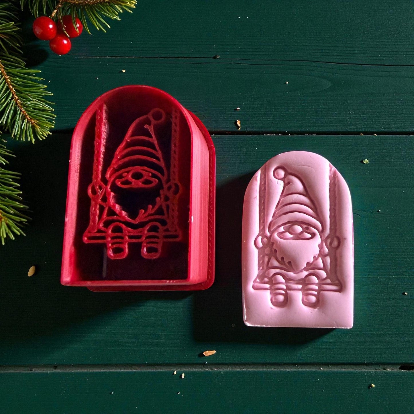 Red cutter and pink gnome clay impression side by side on green background