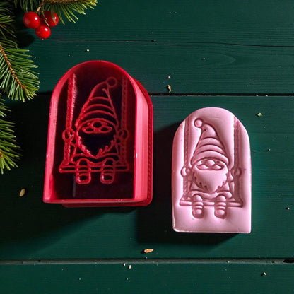 Red cutter and pink gnome clay impression side by side on green background
