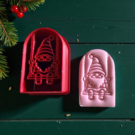 Red cutter and pink gnome clay impression side by side on green background