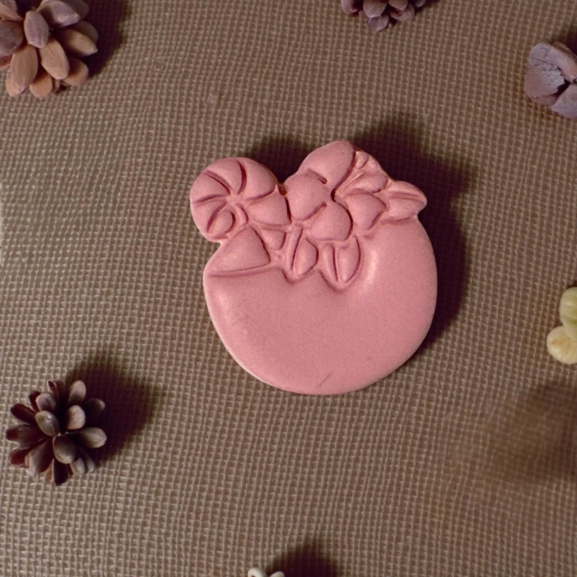 clay drink shape surrounded by mini pinecones