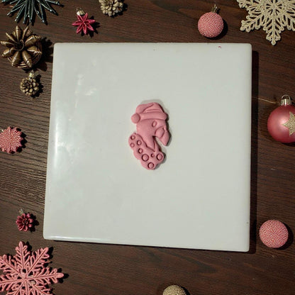 “Flamingo clay piece centered on white tile with holiday decor”