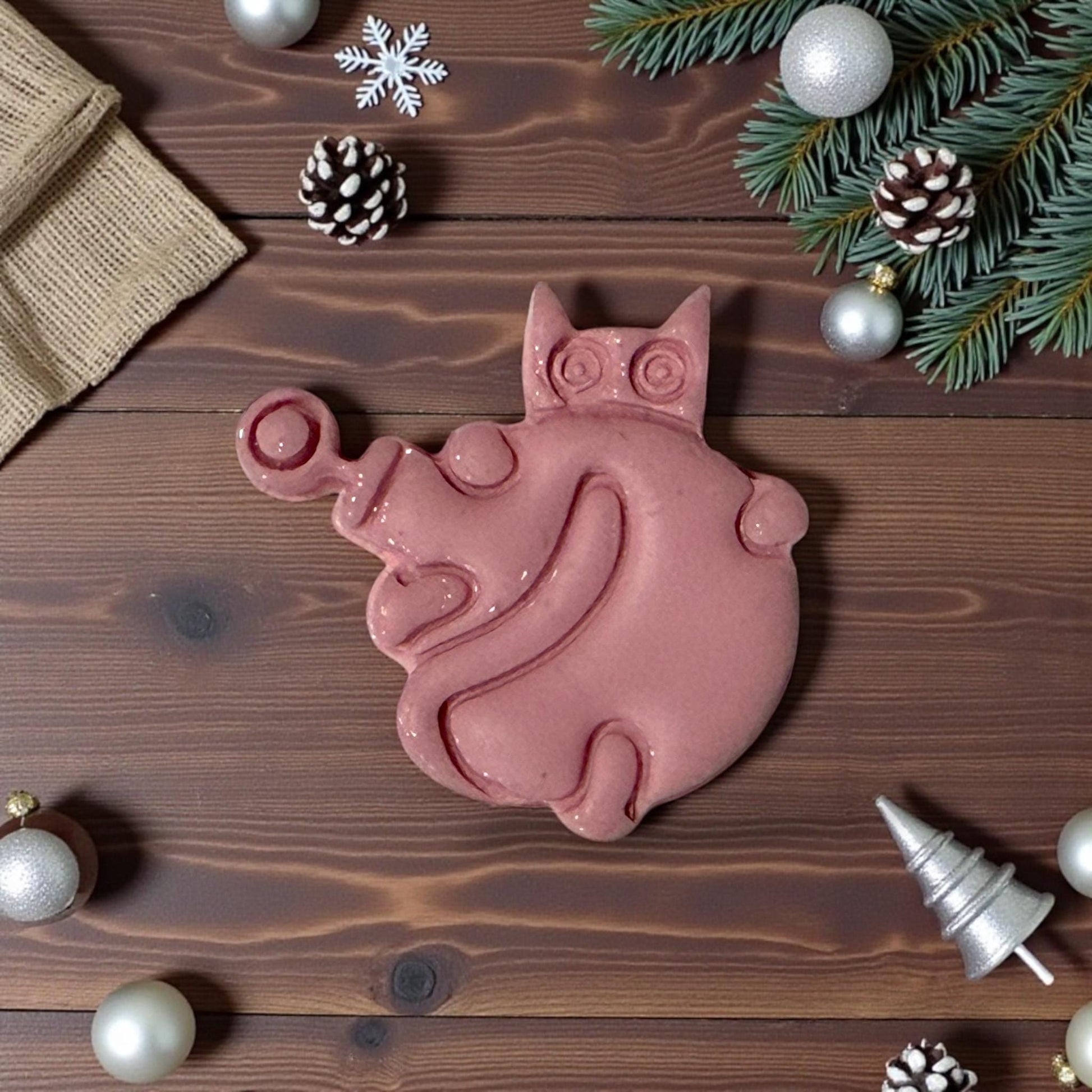 large pink clay cat ornament on rustic wood background