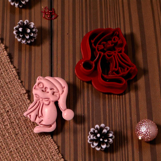 Pink clay impression of Christmas kitty next to cutter