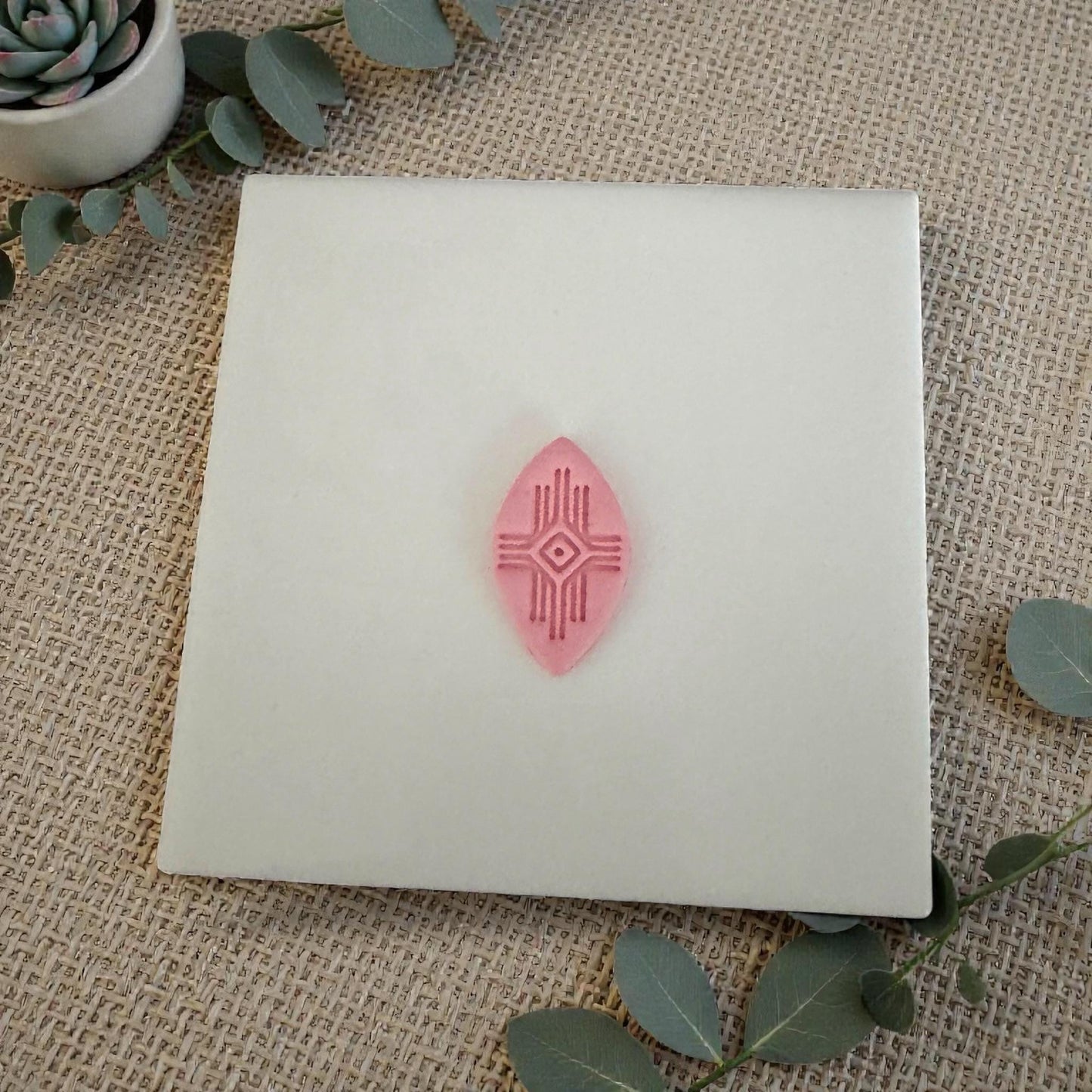 small pink geometric clay piece centered on white tile