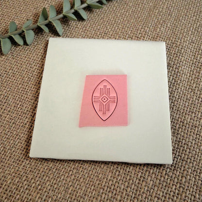 pink clay imprint of tribal geometric design on white tile