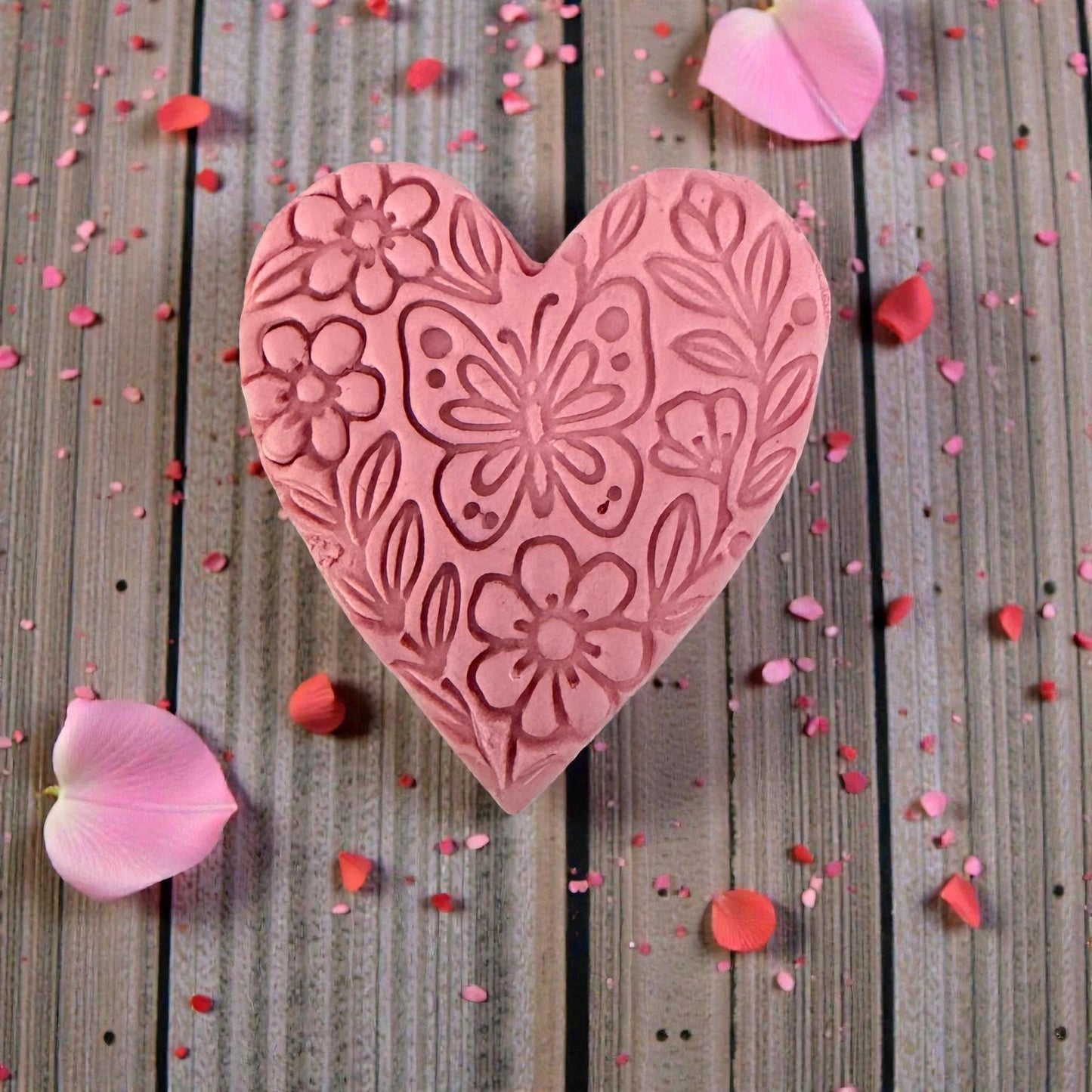 close up of floral butterfly heart impression in pink clay