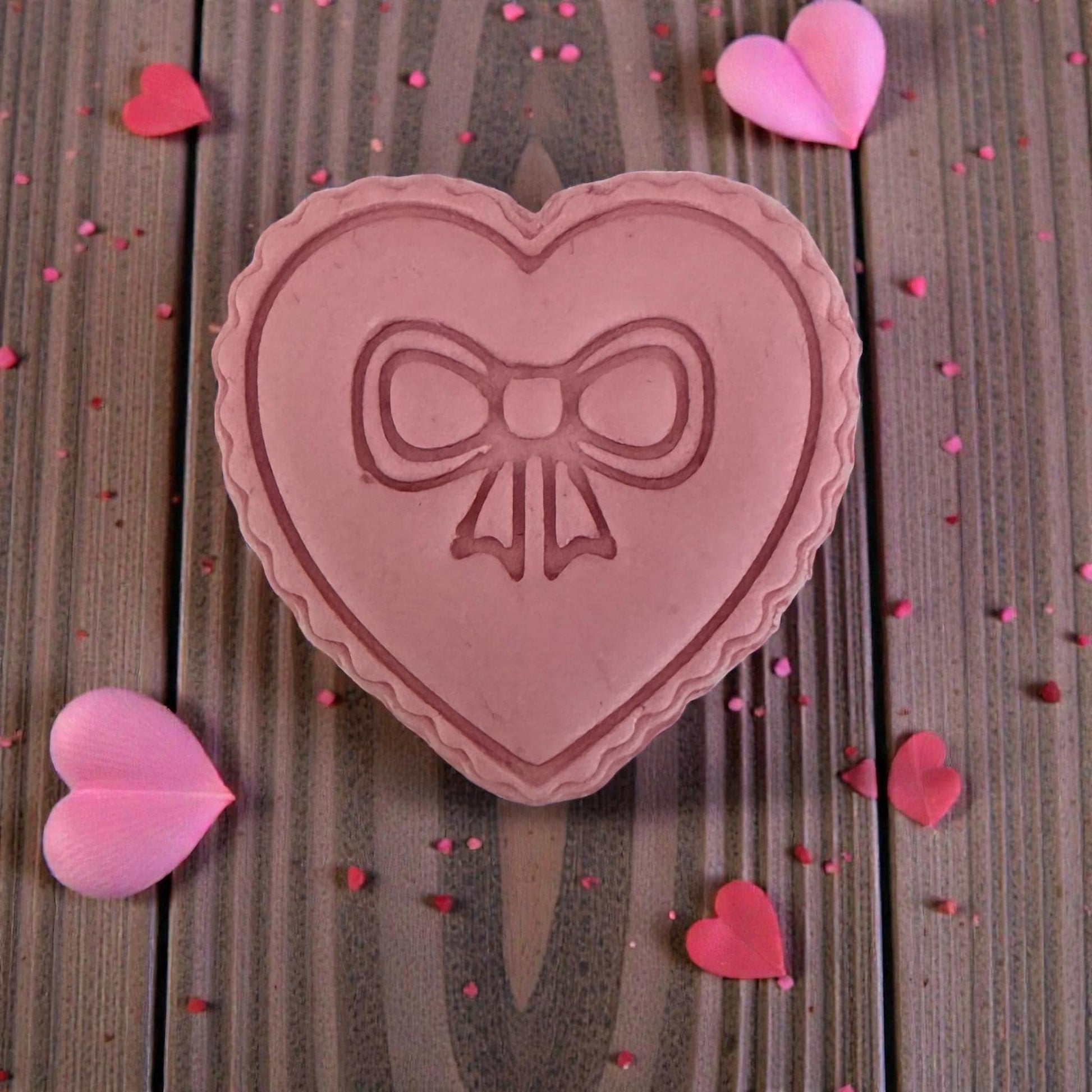 Large clay impression of scalloped heart bow on wooden background
