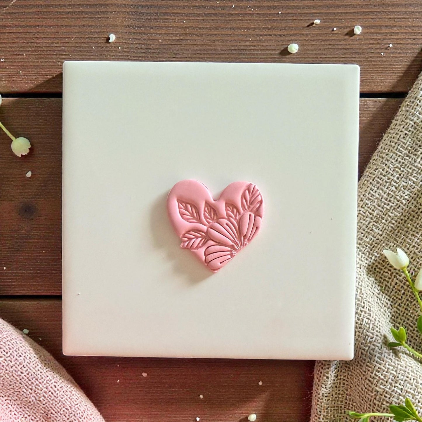 Pink clay heart with floral leaf details centered on white tile