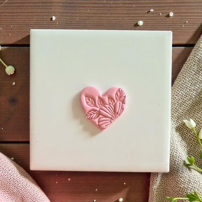 Pink clay heart with floral leaf details centered on white tile