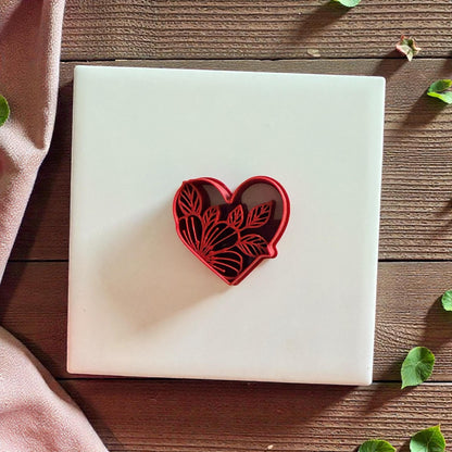 Red floral heart cutter on white tile with soft fabric and wood background