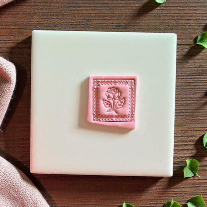 Pink clay rose square with detailed border placed on white tile background