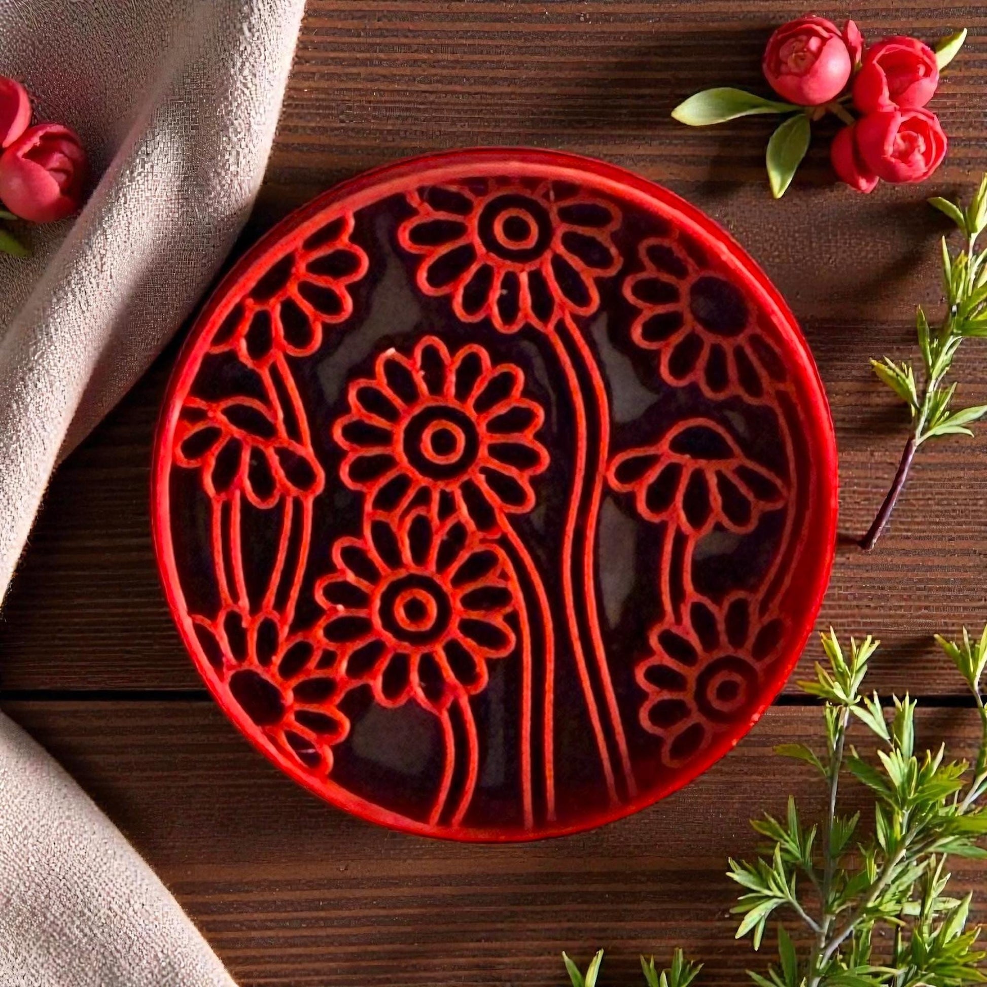 Red daisy meadow polymer clay cutter with floral pattern on wood background and greenery