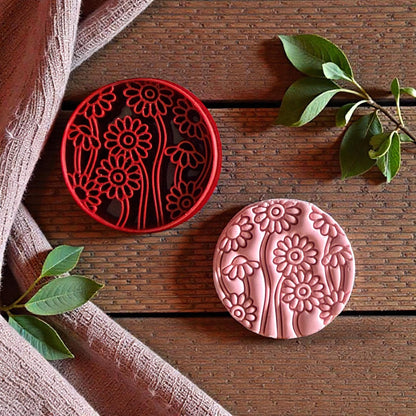 Red cutter and pink clay daisy impression side by side on wood surface