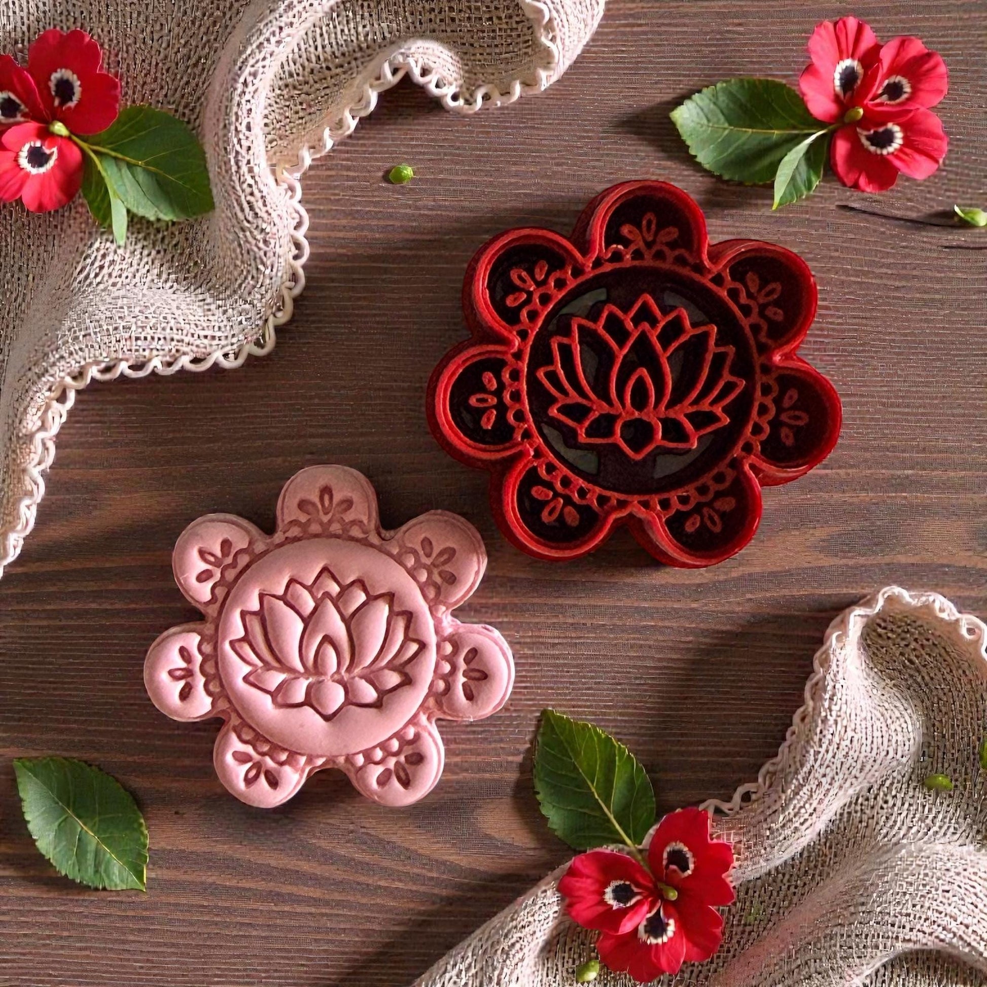 Pink and red lotus mandala clay impressions on wood surface with flowers