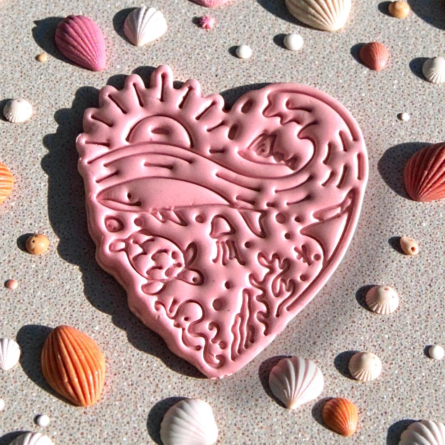 Pink ocean heart clay impression with sea life and waves surrounded by shells