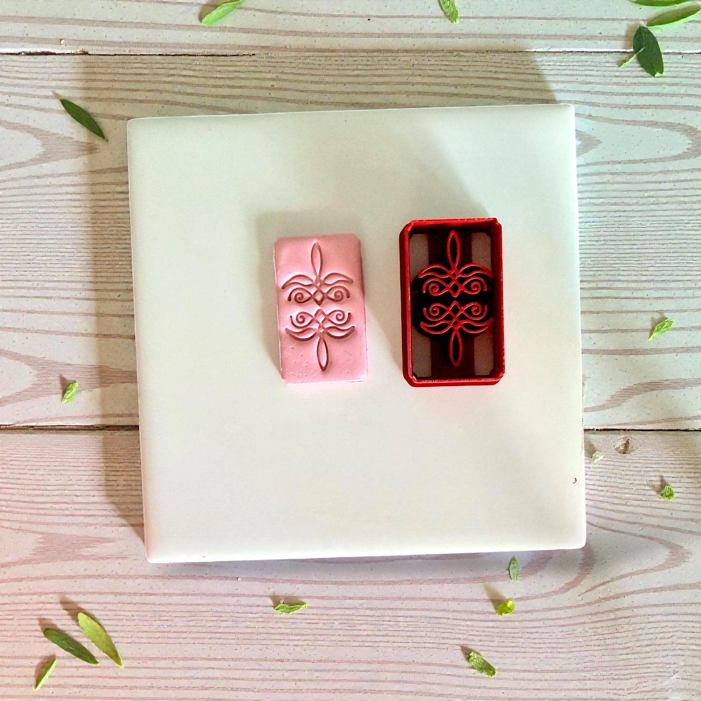 Pink clay impression next to red bootstitch cutter on white tile