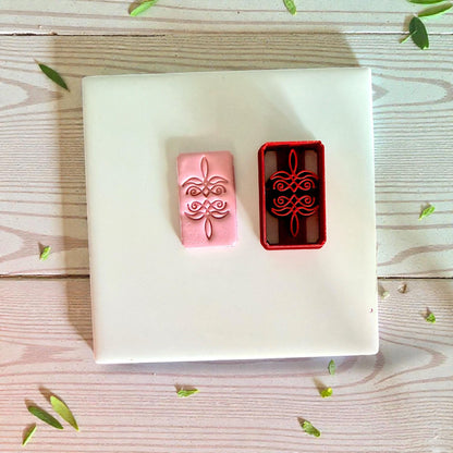 Pink clay impression next to red bootstitch cutter on white tile