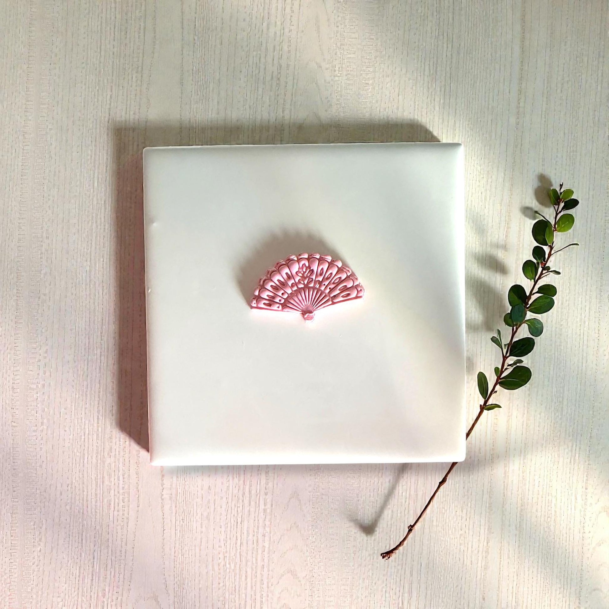 Pink floral fan clay impression centered on white tile