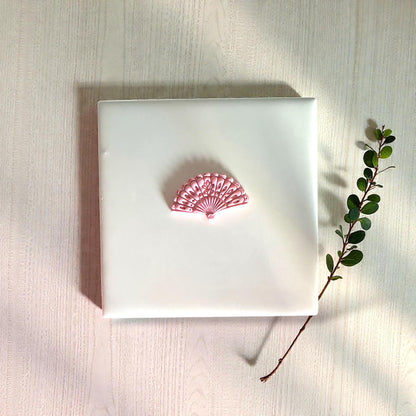 Pink floral fan clay impression centered on white tile