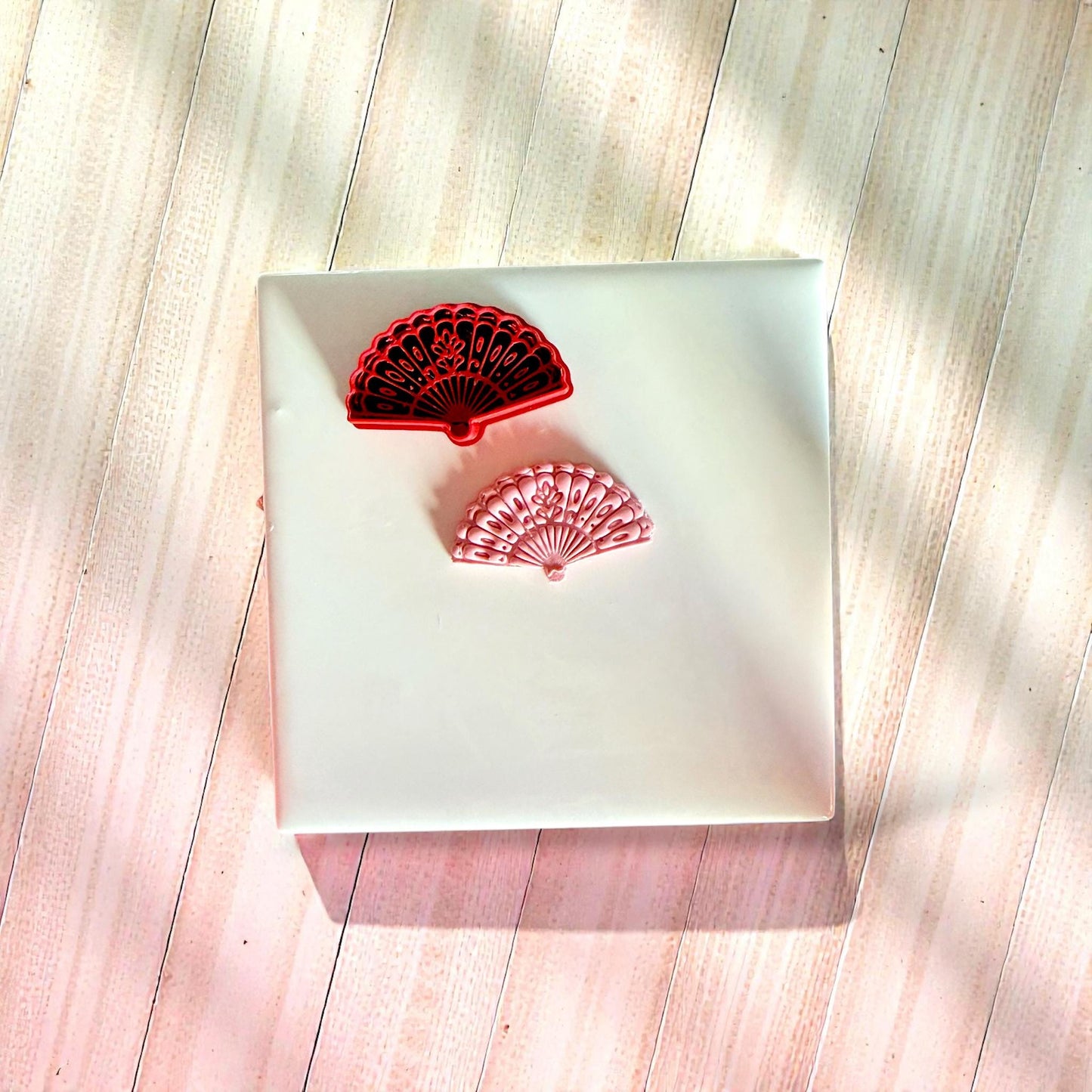 Red floral fan cutter and pink clay impression on white tile