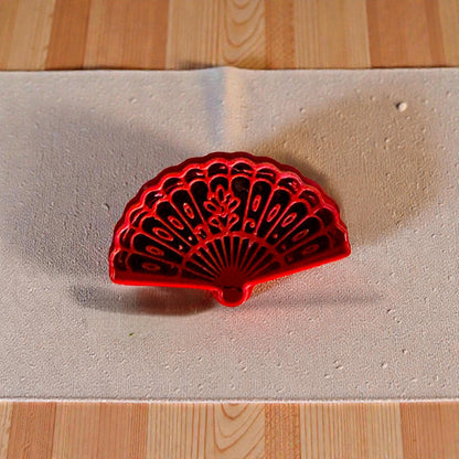 Red floral fan polymer clay cutter on beige textured fabric