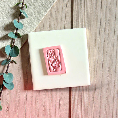 Pink rose blade clay impression on white tile with greenery