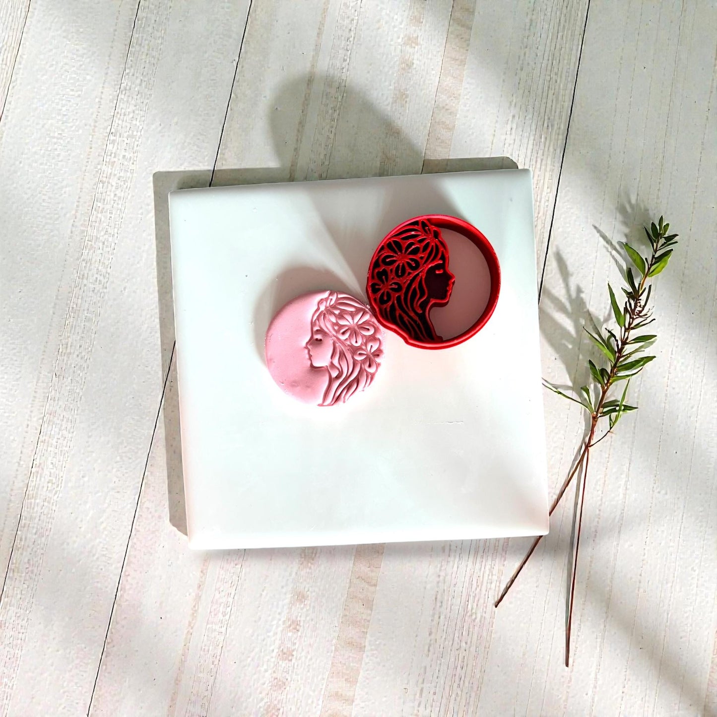 Red floral goddess clay cutter with pink clay impression on white tile