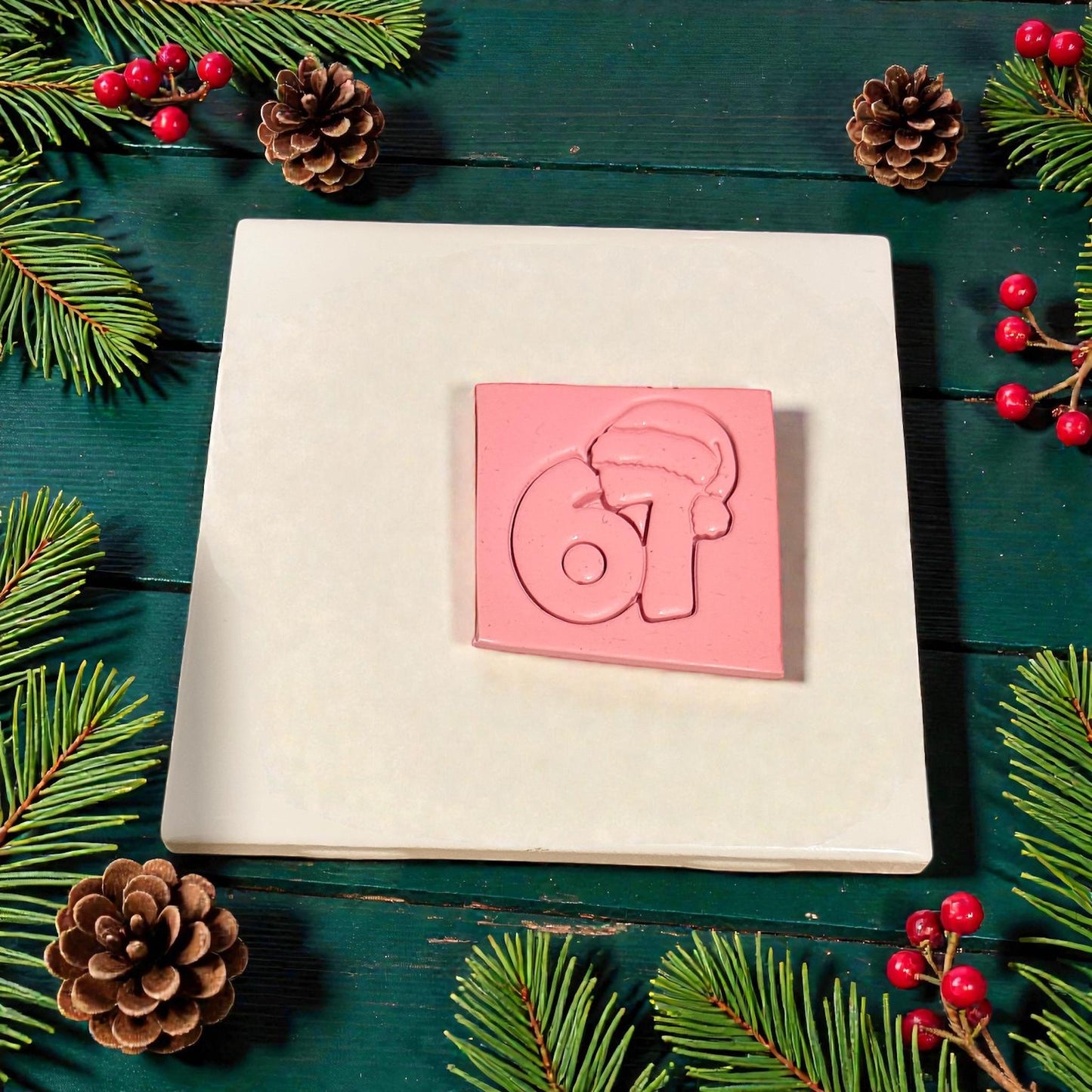 pink clay slab stamped with santa hat 67 design surrounded by pinecones