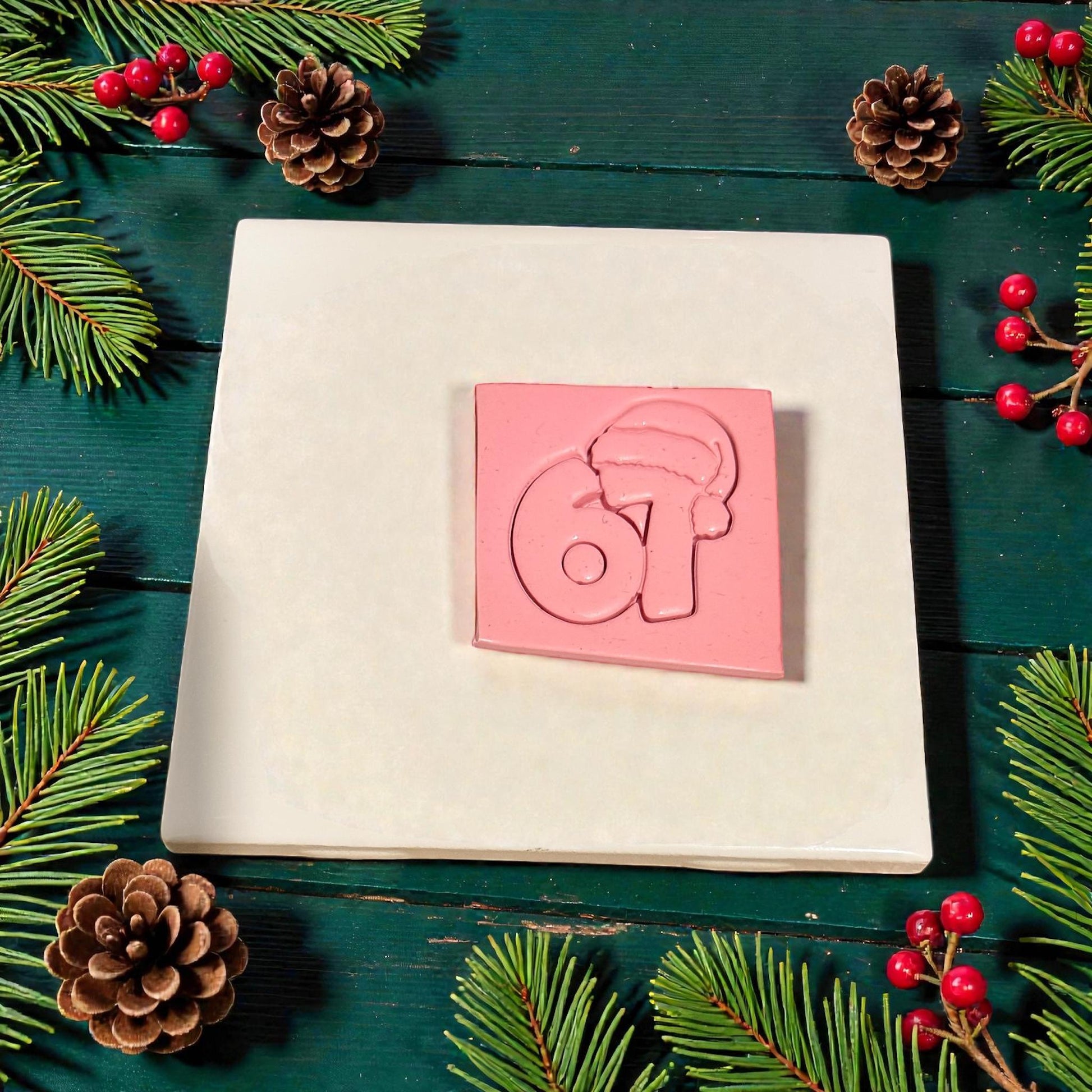 pink clay slab stamped with santa hat 67 design surrounded by pinecones