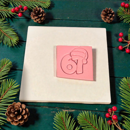 pink clay slab stamped with santa hat 67 design surrounded by pinecones